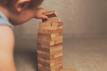 The child's hands pushed the brick and destroyed the tower. Janga wooden box. An imbalance. destruction of blocks. Mistake. Entertainment activities. A game of physical and mental skill