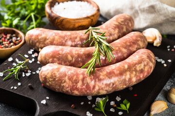 Bratwurst or sausages on cutting board with spices and herbs.