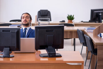 Young male employee in multitasking concept