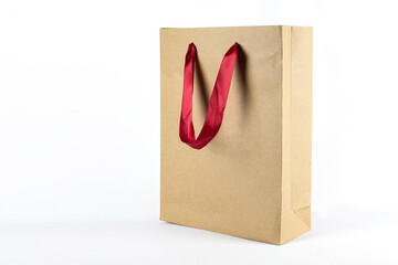 Paper package made of natural kraft cardboard with red bright handle, large paper bag on a light background