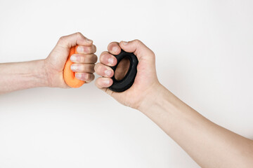 Two hands on a light background compete with each other - squeeze expanders to develop hand strength, the concept of competition, cooperation
