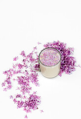 Cup of hot morning coffee and lilac petals on a white background. Copy space for text. Concept of holidays and good morning wishes.