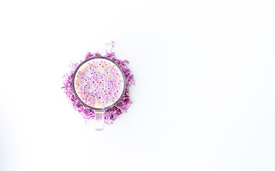 Cup of hot morning coffee and lilac petals on a white background. Copy space for text. Concept of holidays and good morning wishes.