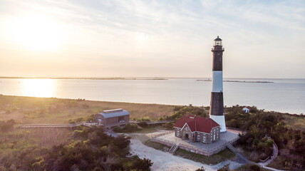 Black and white lighthouse on the ocean as the sun is setting