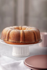 Round cupcake with a hole on a white dish, sprinkled with powdered sugar