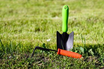 Gardening hand tools scoop and small rake in the garden on the grass