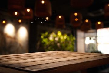 Naklejka na ściany i meble empty wooden table on blurred light gold bokeh of cafe-restaurant window on dark background, place for your products, blurred cafe interior.