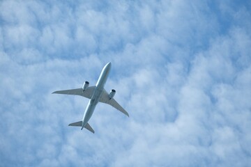 Looking up at  bottom of airplane with fluffy white clouds