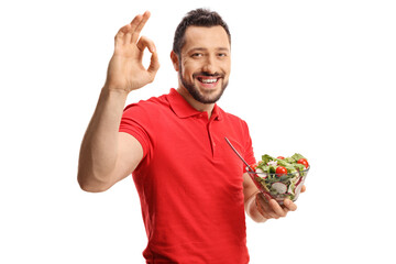 Young man in a red t-shirt holding a fresh salad in a bowl and gesturing good sign