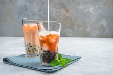 Bubble tea, making a Taiwanese drink with tapioca, milk and ice on a gray background. Side view. A refreshing, healthy drink.