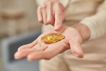 Old woman holds bitcoin coins in her hand. Senior citizen happy life concept