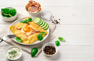 Breakfast with pancake, egg and bacon on a light background. Breton crepe. Side view, copy space.