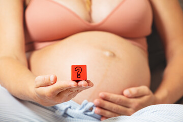Question mark in pregnant woman hand near belly