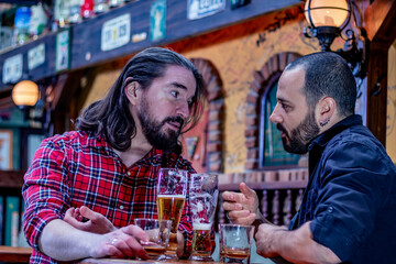 Two male friends drinking whiskey and beer together at the pub. They are drunk and they are talking, and comforting each other.