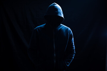 a man in a hood stands on a black background