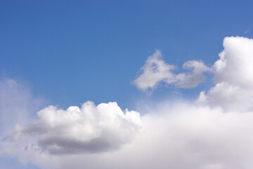 A few white clouds in the blue sky, one small to the left of the center. the bulk of the clouds at the bottom.