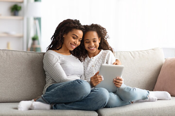 Cute african american mother and kid using digital tablet together