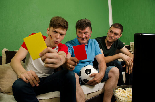 Family Die Hard Soccer Fans, Sitting In Front Of Tv With Face Paint On And Judge Cards Yellow And Red 