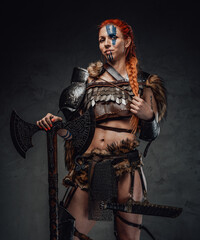 Serious nordic female warrior with axe and armour in dark background