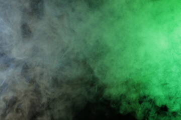 Artificial smoke in grey-green light on black background