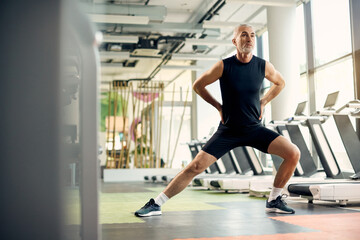 Fototapeta na wymiar Mature athletic man warming up for sports training while exercising in a gym.