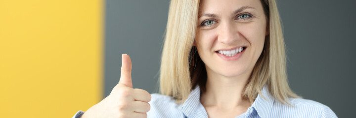 Young woman holding english textbook and showing thumb up