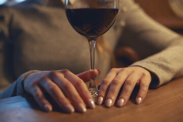 Fototapeta na wymiar Hands of a young beautiful woman holding a glass of wine indoors of a stylish wine restaurant