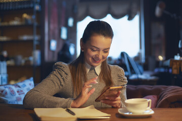 Beautiful woman sitting in a cafe at a table drinking tea and making notes in a notebook