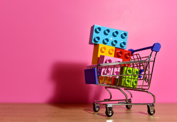 Toy plastic bricks in shopping cart for kids. Plastic construction blocks for children play....