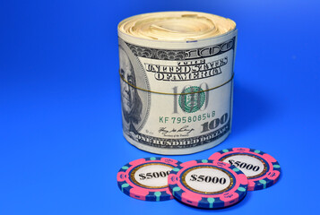 Poker chip for casino game and a bundle of one hundred dollar bills on table. The concept of...