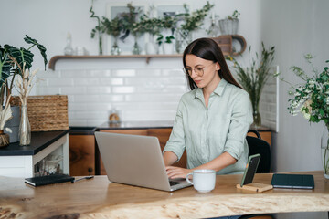 Head shot pleasant happy young woman freelancer working on computer at home. Attractive businesswoman studying online, using laptop software, web surfing information or shopping in internet store.