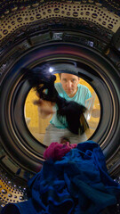 Fototapeta na wymiar VERTICAL: Male doing housework over the weekend is loading up washing machine.