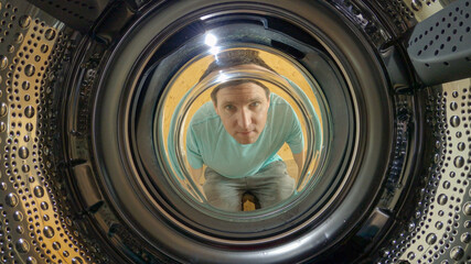 PORTAIT: Caucasian man doing chores on the weekend looks into the empty washer.