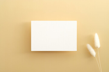 White invitation card mockup with dried flowers on beige background. Greeting card template for wedding, birthday, Mother's Day. Minimal style.