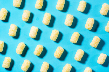 A trendy background of corn sticks on a blue backdrop in harsh light. Top view