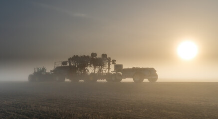 Naklejka premium Farm Seeding equipment travelling down the road on a foggy morning