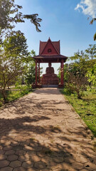 Fototapeta premium Way to Buddha statue in the gazebo in the park. Cambodia. South-East Asia