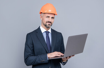 businessman man in building helmet texing message on laptop, business communication