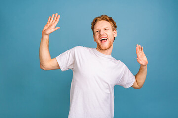 Yeah! Happy winner! Happy young handsome man celebrating victory gesturing and keeping mouth open while standing isolated over blue background.