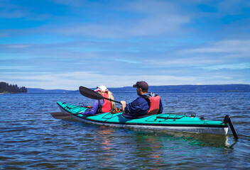 Recreational kayaking. The view on the young couple in double kayak sailing on the ocean, watching...