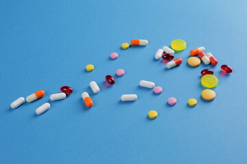 Multicolored medical pills of various shapes on a blue background