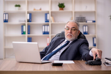 Fototapeta premium Old male employee working in the office