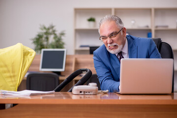 Aged businessman employee looking after newborn at workplace