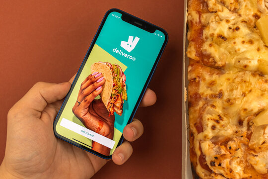 Kharkov, Ukraine - May 28, 2021: Man Hold Mobile Phone With Deliveroo Food Delivery App On The Screen