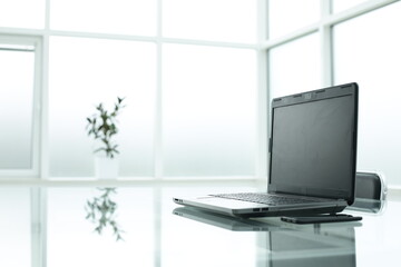 Laptop on glass table in spacious office space