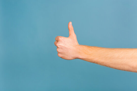 Close-up photo of man showing thumbs up. Isolated over blue background.