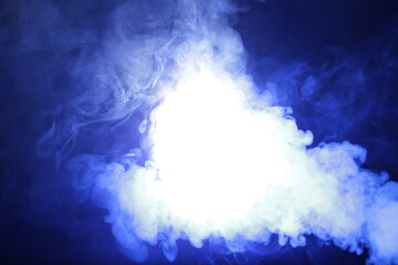 Artificial smoke in blue light on black background