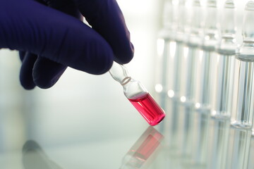 Doctor in rubber blue gloves picks up a bottle of vaccine with his fingers