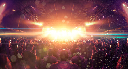 Concert crowd inside a venue, lens flare and smoke are visible.