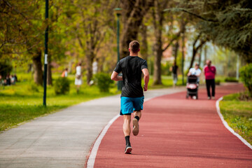 Good looking young Hispanic man jogging at a park on a sunny day and smiling